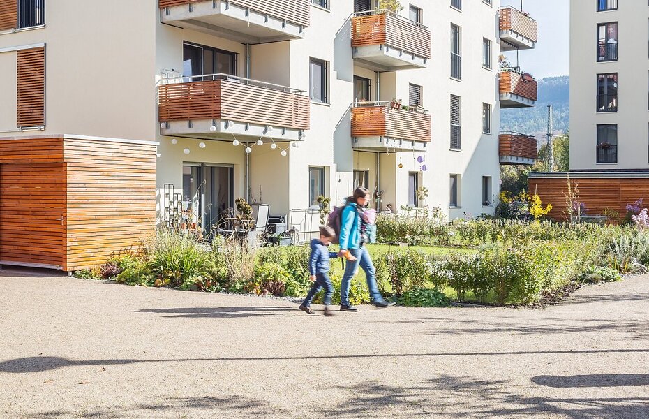 Wohngebäude der Gartenstadt 2.0 – Quartier Immergrün in Jena mit Balkonen, Grünflächen und Fußweg