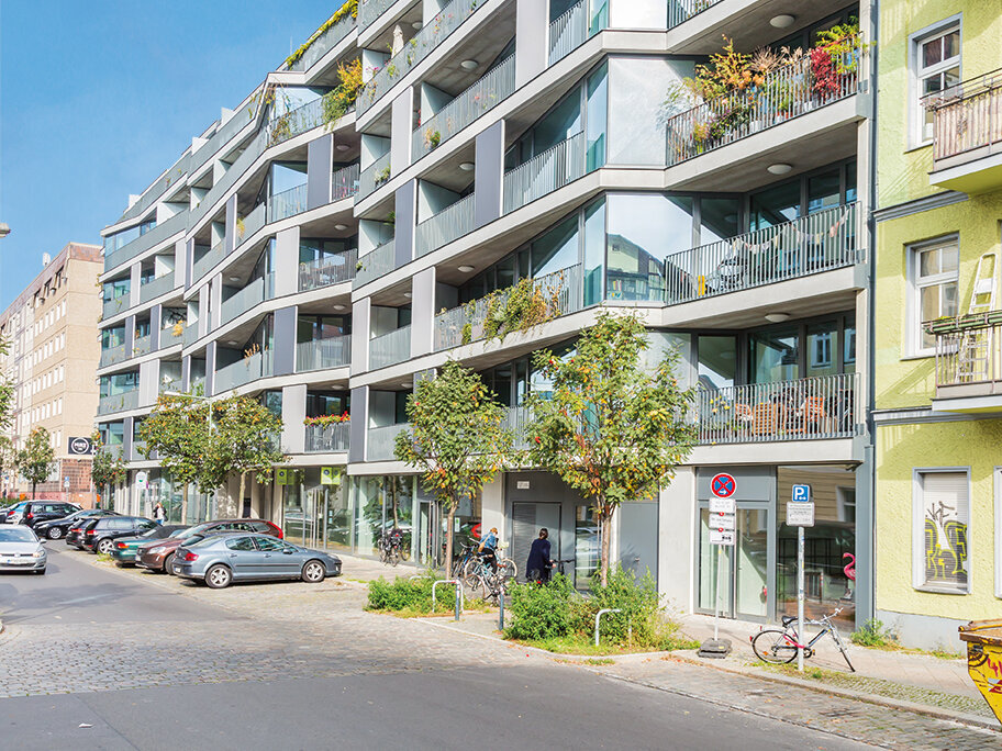 Straßenansicht eines Wohngebäudes in Berlin-Friedrichshain mit verglasten Erkern, Balkonen und Erdgeschossnutzung
