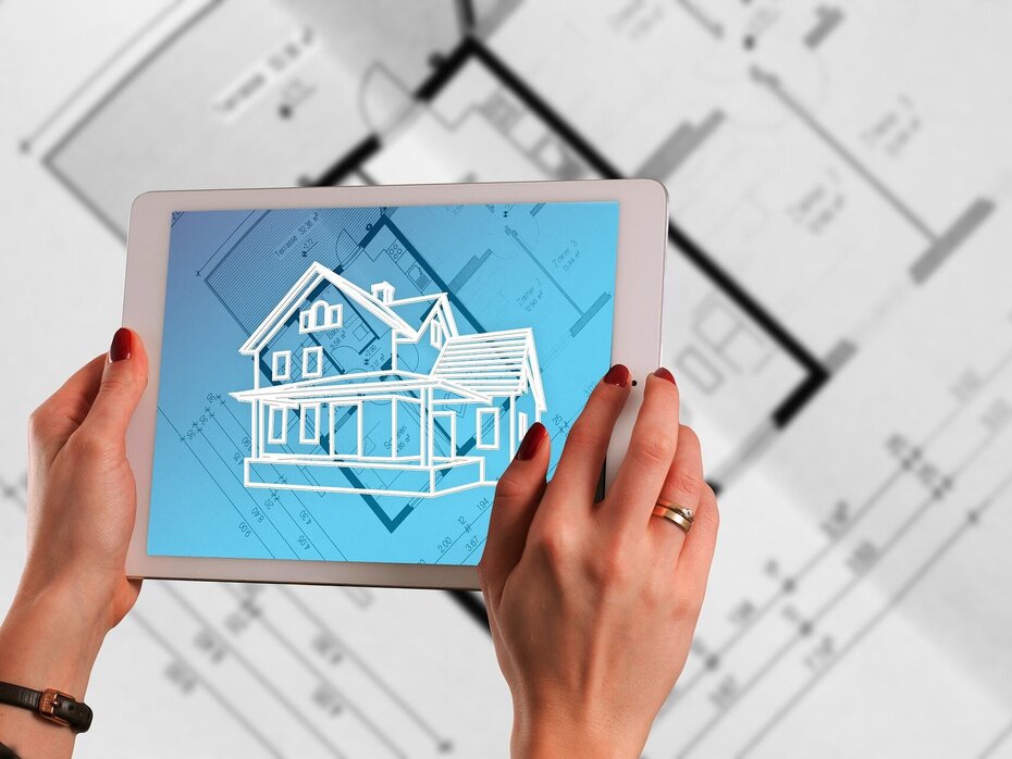 Tablet mit Hauszeichnung auf einem Bauplan als Symbol für Planung und funktionsgetrennte Außenwände mit Kalksandstein.